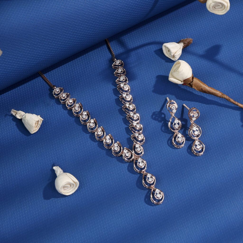 Professional jewellery product photography featuring a rose gold diamond necklace and matching earrings displayed on a blue textured backdrop with white roses, ideal for eCommerce, catalog, and luxury jewellery marketing.